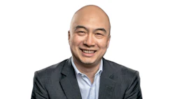 Professional headshot of a smiling Asian man in business attire against white background