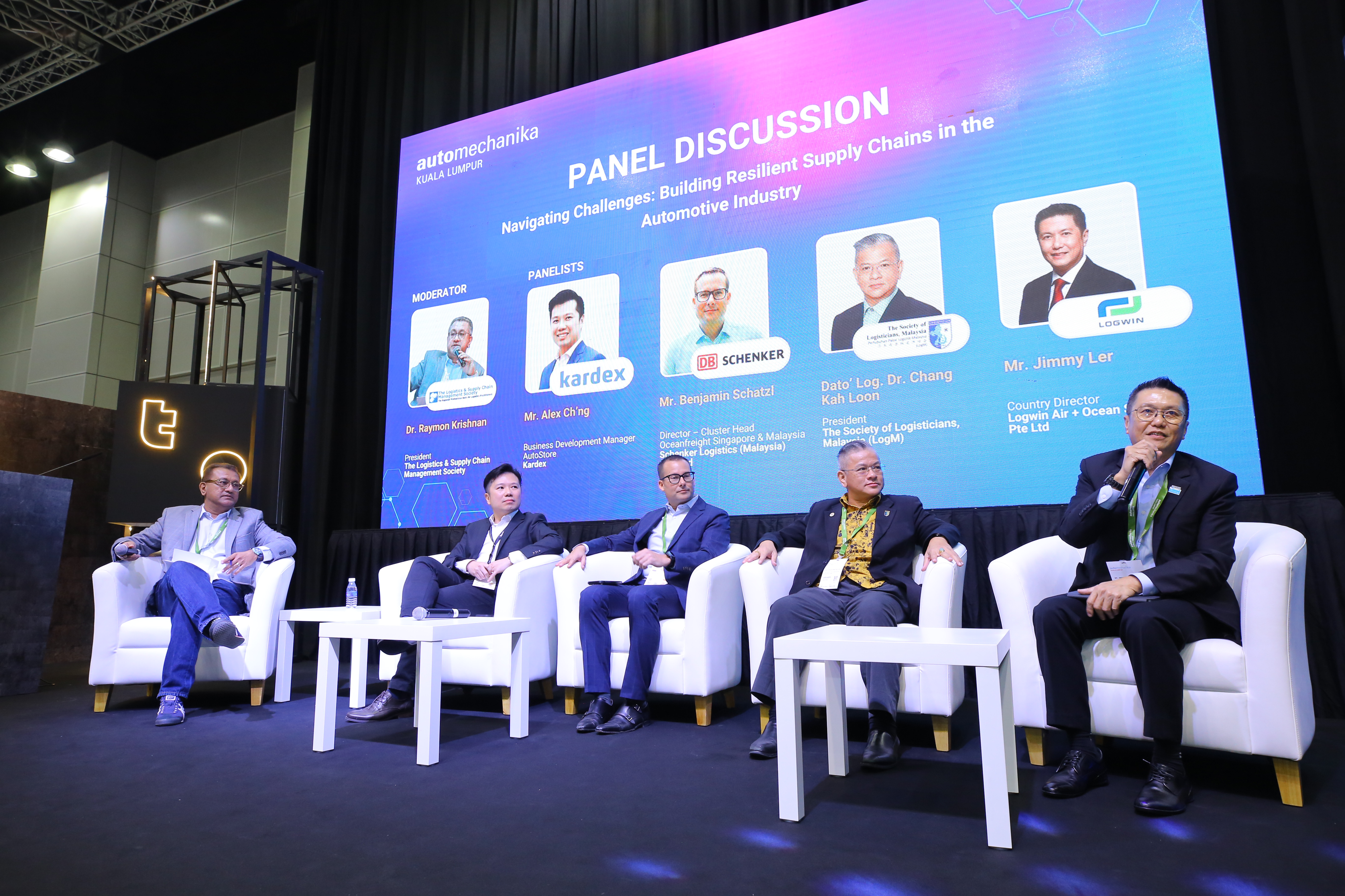 Five panelists seated on stage during automotive industry supply chain discussion panel at corporate conference event