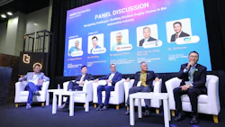 Five panelists seated on stage during automotive industry supply chain discussion panel at corporate conference event