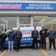 Novus Tires team posing in front of storefront with branded service vehicle