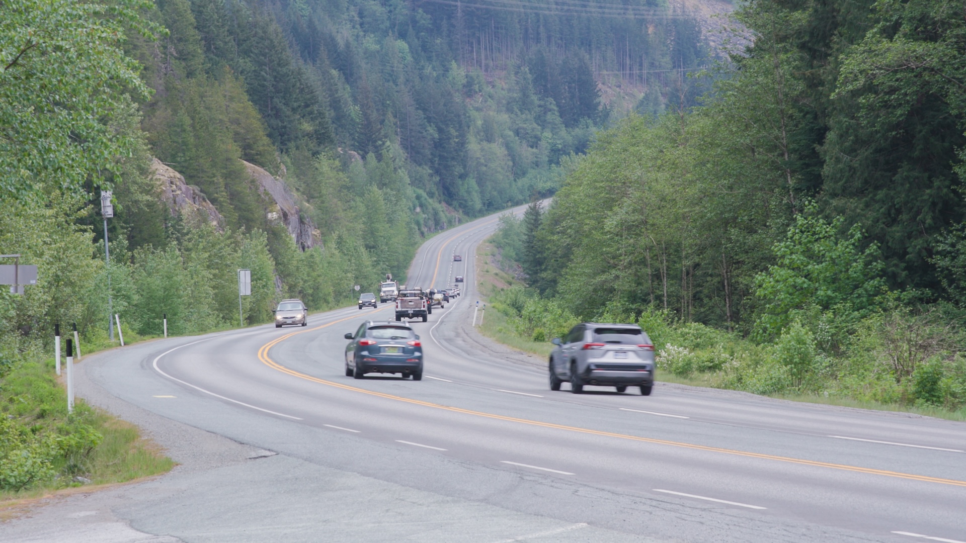 Mountain highway with vehicles traveling through forested valley with winding road