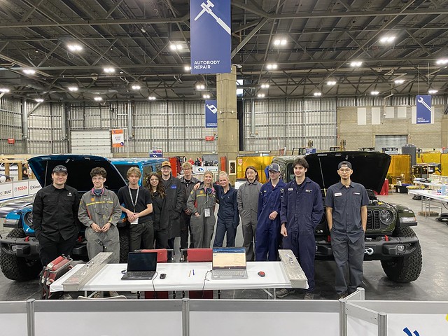 Team members pose in front of modified vehicles and equipment at Autonomy Robotics facility