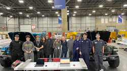 Team members pose in front of modified vehicles and equipment at Autonomy Robotics facility
