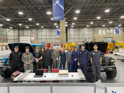 Team members pose in front of modified vehicles and equipment at Autonomy Robotics facility
