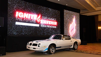 White Pontiac Firebird sports car displayed at indoor event venue with neon signage backdrop