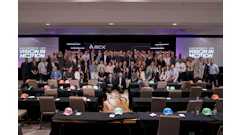 Large group photo from ACX Audio Conference with attendees standing on stage, colorful hard hats on tables, and ACX branding backdrop
