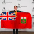 Young woman holding Ontario flag and wearing gold medal at Skills/Compétences Canada competition event