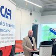 Instructor conducting EV training session in workshop with IFCAR signage and electrical equipment visible