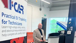 Instructor conducting EV training session in workshop with IFCAR signage and electrical equipment visible