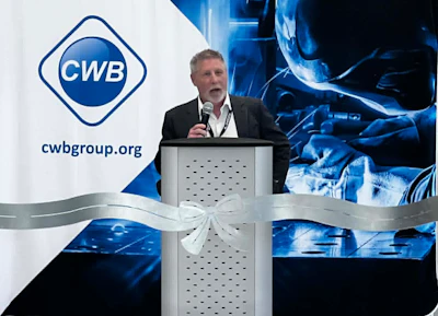 Professional speaker at podium during CWB Group corporate event with blue technology-themed backdrop