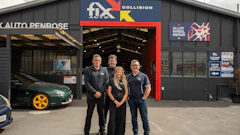 Four employees standing in front of Fix Auto Collision repair shop with red entrance and signage