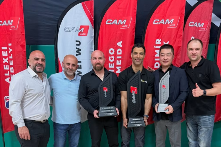 Six men posing at professional event with red CAM branded banners in background