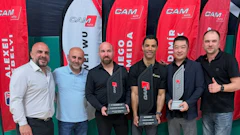 Six men posing at professional event with red CAM branded banners in background