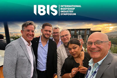 Six professionals smiling at IBIS symposium event with sunset cityscape backdrop