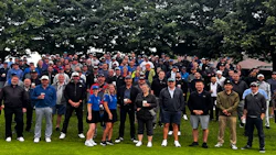 Large group of people standing together on a grass field at an outdoor event or gathering