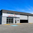 Klimat industrial warehouse facility with white metal exterior and service bay doors under clear blue sky