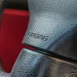 Airbag embossed text on gray leather car steering wheel with red interior visible