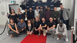 Group of diverse professionals posing together at corporate event with ASCX backdrop and red carpet