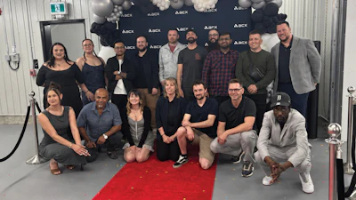 Group of diverse professionals posing together at corporate event with ASCX backdrop and red carpet