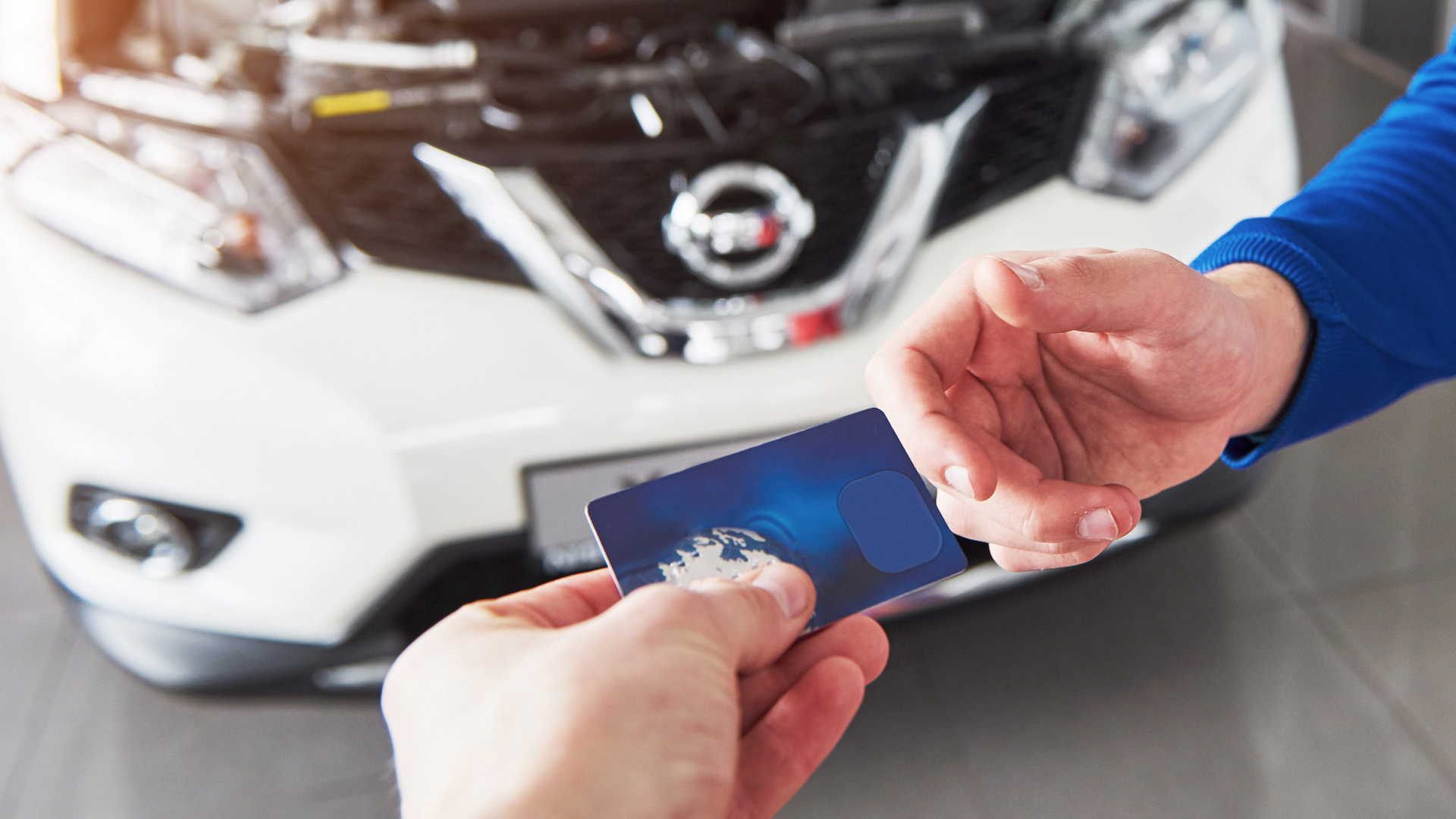 Person holding smartphone displaying car interface with white vehicle in background