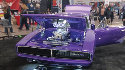 Purple classic car with chrome engine displayed at automotive show with spectators