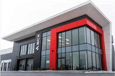 Modern commercial building with red and black facade featuring ABCX branding and large glass windows