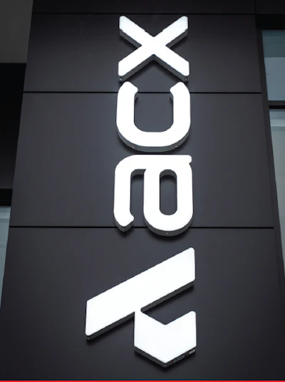 NEXT retail brand storefront sign with white geometric logo and text on dark facade