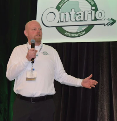 Man in white shirt speaking at podium with Ontario Motorcyclist Association logo displayed behind him