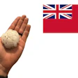Hand holding a spherical seed ball with Canadian Red Ensign flag in background