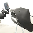 Worker spray painting black automotive part using HVLP spray gun in industrial facility