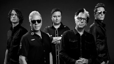 Five-member band posed in black and white studio portrait with dark background