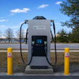 Astray electric vehicle charging station with dual connectors flanked by yellow safety bollards in a parking lot