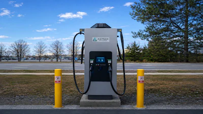 Astray electric vehicle charging station with dual connectors flanked by yellow safety bollards in a parking lot