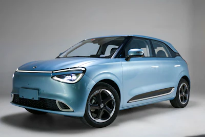 Light blue compact electric vehicle displayed in three-quarter view against neutral background