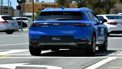 Blue Chevrolet Equinox electric SUV parked in urban lot with white sedan nearby