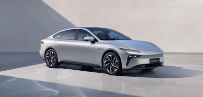 White electric sedan displayed in minimalist studio setting with dramatic shadow lighting