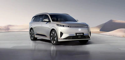 White electric SUV displayed on reflective surface with desert mountains in background