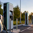 White electric vehicle charging at modern EV charging station during golden hour sunset with multiple chargers in a row