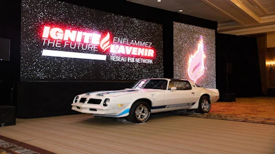 White Pontiac Firebird sports car on display at IGNITE corporate event with illuminated branded signage