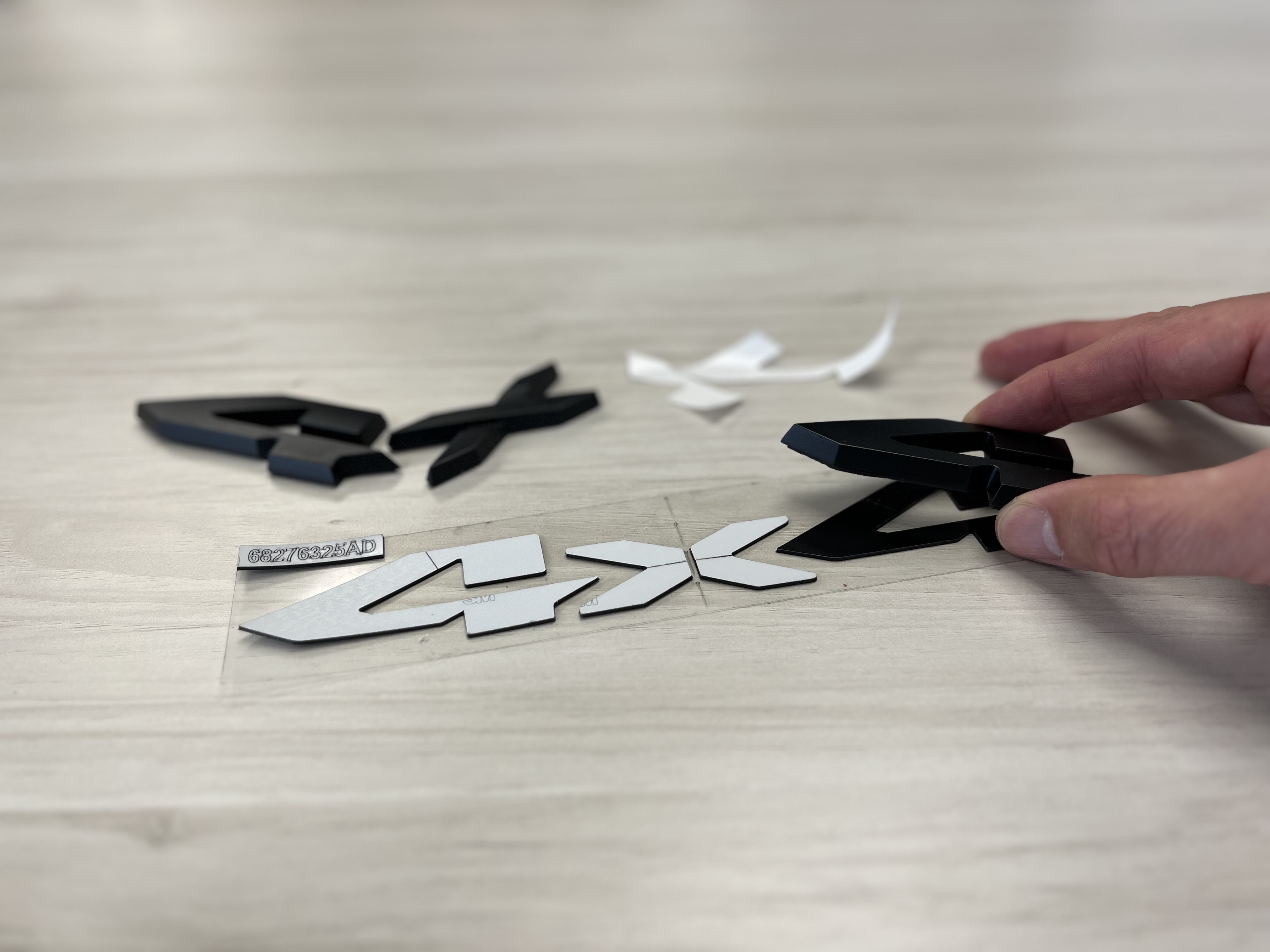 Hand cutting apart a black logo with scissors on wooden surface with scattered pieces
