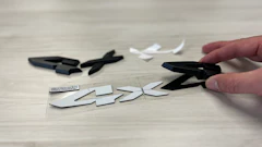 Hand cutting apart a black logo with scissors on wooden surface with scattered pieces