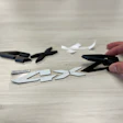 Hand cutting apart a black logo with scissors on wooden surface with scattered pieces