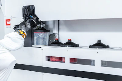 Automated laboratory analyzer with robotic arm, reagent containers, and waste disposal system on white surface