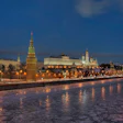 Moscow Kremlin illuminated at dusk with golden-lit towers reflected in the frozen Moscow River