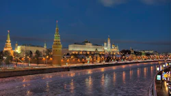 Moscow Kremlin illuminated at dusk with golden-lit towers reflected in the frozen Moscow River
