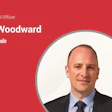 Mike Woodward, Chief Financial Officer at AutoCanada, professional headshot on red background