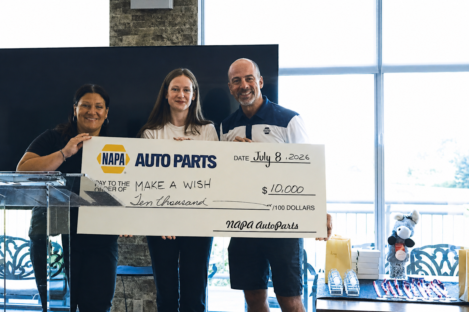 Three people holding a $10,000 NAPA Auto Parts donation check for Make a Wish Foundation on July 8, 2026