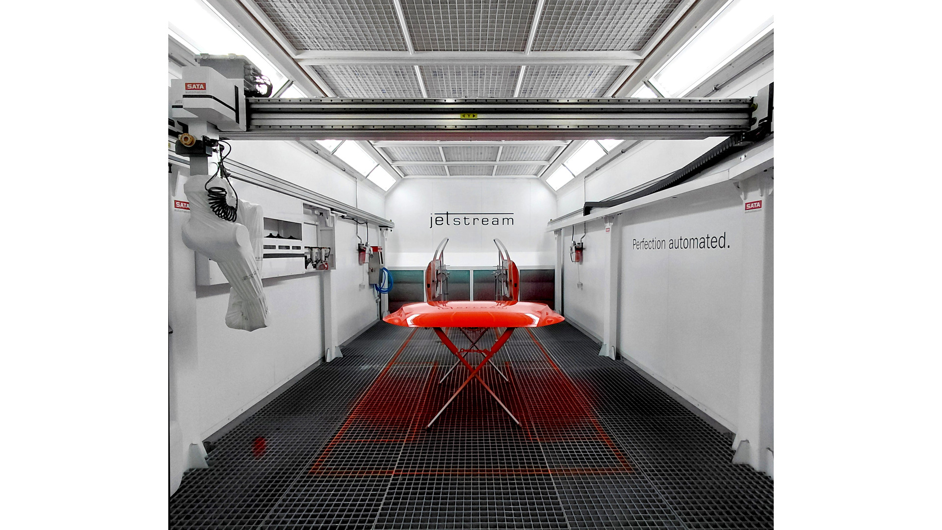 Modern automotive paint booth with red vehicle on lift, overhead crane system, and industrial workspace