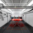 Modern automotive paint booth with red vehicle on lift, overhead crane system, and industrial workspace