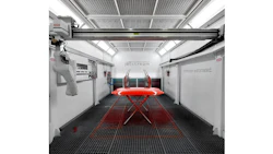 Modern automotive paint booth with red vehicle on lift, overhead crane system, and industrial workspace